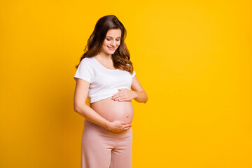 Photo of adorable lady waiting baby dressed white clothes embracing naked tummy isolated yellow...