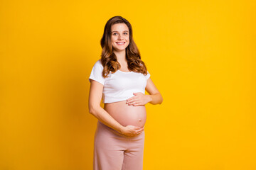 Photo of sweet lady waiting baby dressed white clothes embracing naked tummy isolated yellow color background