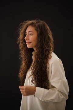 Studio shot of smiling young woman with long curly hair