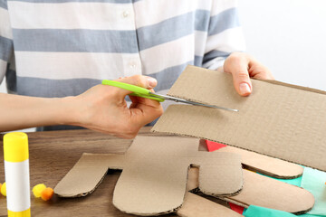 Woman making cardboard cactus at wooden table, closeup. Pinata DIY © New Africa