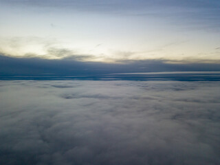 High flight above the clouds at sunset. Aerial view.