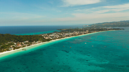 White sandy beach with turquoise water and tourists on Boracay Island, top view. Tropical white beach with sailing boat. Summer and travel vacation concept.