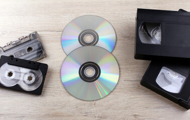 Various old storage media. Discs, old audio and video tapes on wooden background