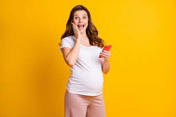 Fototapeta na wymiar Portrait of pretty amazed cheery pregnant girl using gadget fast speed 5g notification isolated over bright yellow color background