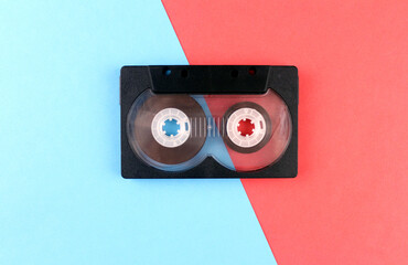 Old black audio cassette on red and blue background