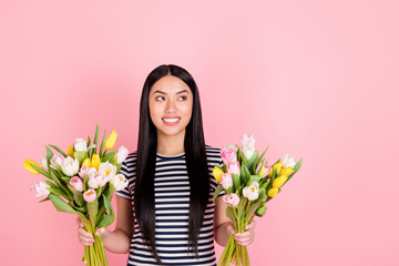 Photo portrait of asian girl looking blank space dreamy smiling keeping two tulips bunches isolated pastel pink color background