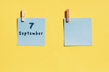 7 September. 7th day of the month, calendar date. Two blue sheets for writing on a yellow background. Top view, copy space. Autumn month, day of the year concept