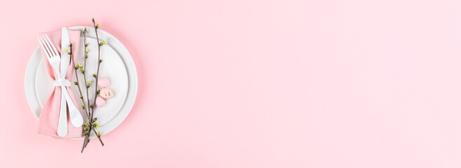 Easter holiday table setting on a pink paper background.Plates with colorful eggs. Easter holiday concept .Top view, copy space.Banner