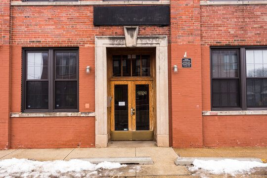 Vintage doorway with wooden doors attached to old red brick industrial building in urban Chicago