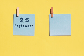 25 september. 25th day of the month, calendar date. Two blue sheets for writing on a yellow background. Top view, copy space. Autumn month, day of the year concept