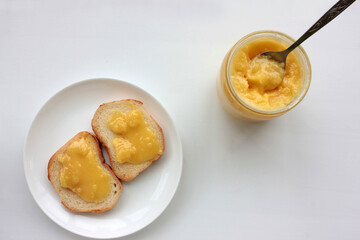 Toast bread with organic honey on plate and glass jar of honey on white table background. Healthy breakfast concept. Top view, copy space.