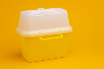 Yellow syringe pen container with white cap on seamless yellow background for the disposal of used injector needles with drug residue. Studio medical equipment still life concept. © Maarten Zeehandelaar