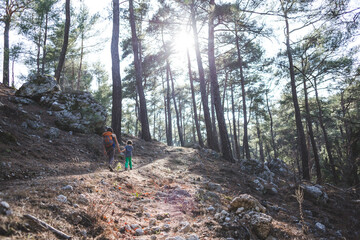 A woman walks with her son through the forest.