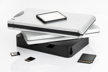 Group of external Hard disks and memory cards on white table. Data storage concept