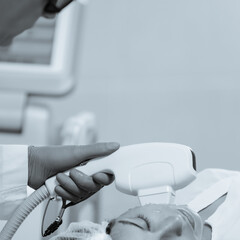 Woman receiving face skin phototherapy procedure in clinic of aesthetic cosmetology. black and white image with blue tint to emphasize the concept of high technology