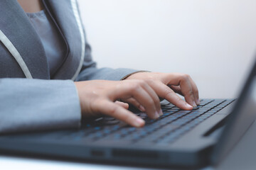 close-up of business woman hand typing and using laptop keyboard for searching with technology networking on working and job on desk at work place or work at home.