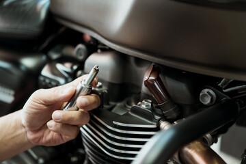 Mechanic Check motorcycle Spark Plug and Maintenance, inspection Prior to Installation in engine ignition at motorcycle garage.repair and maintenance motorcycle concept.