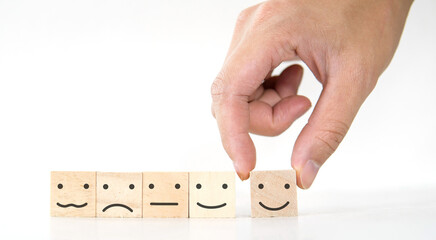 Concept of customer service, hand holding smile face icon on wood