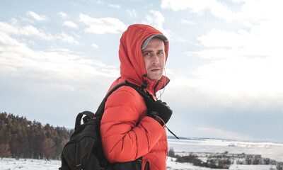 A guy with a briefcase on the background of a pine forest in winter. The man in the orange jacket