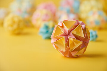 Set of multicolor handmade modular origami balls or Kusudama Isolated on yellow background. Visual art, geometry, art of paper folding, paper crafts. Close up, selective focus, copy space.