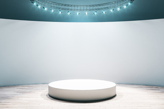 White round podium in the center of empty hall room with parquet floor, light wall and led light on top. Mock up © Who is Danny