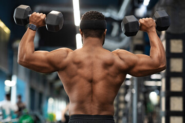 Back view of african american shirtless man exercising at gym