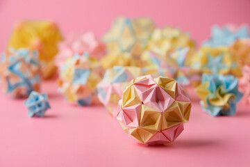 Set of multicolor handmade modular origami balls or Kusudama Isolated on pink background. Visual...