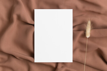 White invitation card mockup with a lagurus decoration on the textile. 5x7 ratio, similar to A6, A5.
