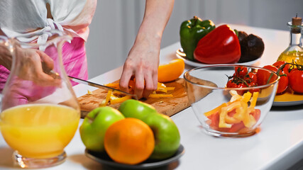 partial view of woman cutting bell pepper on chopping board