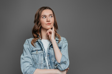 Caucasian student girl thinking and looking away isolated on dark grey background in studio. Concept idea. Copy space