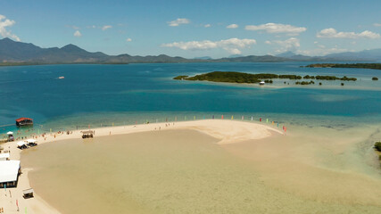 Obraz premium Beautiful beach on tropical island surrounded by coral reef, sandy bar with tourists. honda bay top view. Luli island. Summer and travel vacation concept, Philippines, Palawan