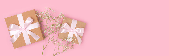 Banner with gift boxes with a tied ribbons and branch of gypsophila flower on a pink background. Congratulation concept with copyspace.
