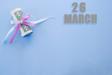 calendar date on blue background with rolled up dollar bills pinned by blue and pink ribbon with copy space. March 26 is the twenty-sixth day of the month