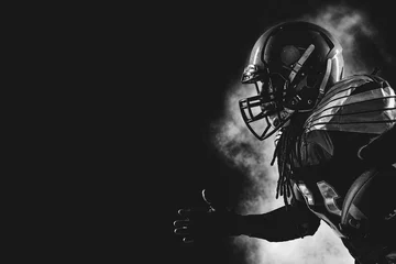 Fotobehang American football player. Sportsman with ball in helmet on stadium in action. © romanolebedev