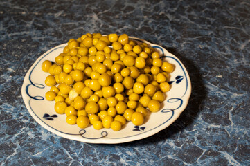 Tinned green peas on a white plate. Peas for food. Dark blue background.