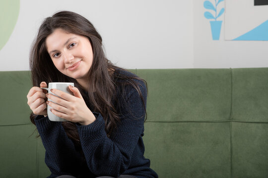 Portrait of brunette girl in black sweater sitting on couch 