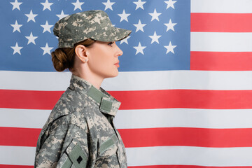 Side view of woman in camouflage uniform near american flag at background