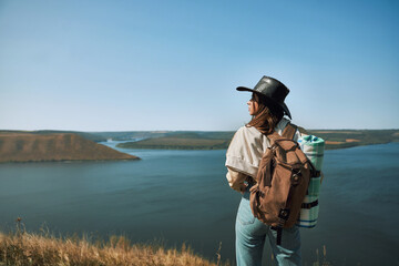Obraz premium Woman with backpack standing on top of hill