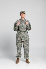 Military woman with backpack looking at camera on grey background