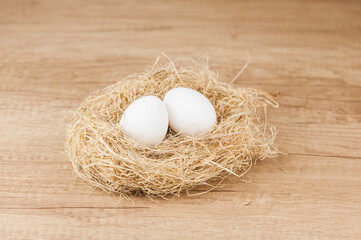 white chiken eggs in nest on wooden table with copy space