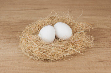 white chiken eggs in nest on wooden table with copy space