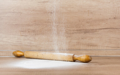 Spilled white flour and wooden rolling pin at the kitchen table . Free place to paste text/title