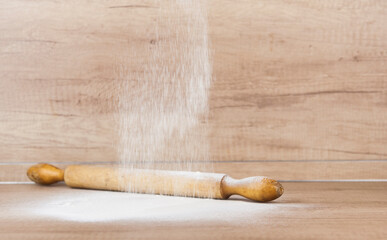 Spilled white flour and wooden rolling pin at the kitchen table . Free place to paste text/title