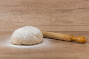 homemade pizza dough with rolling pin on the wooden table
