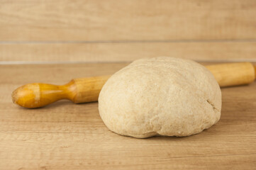 homemade pizza dough with rolling pin on the wooden table