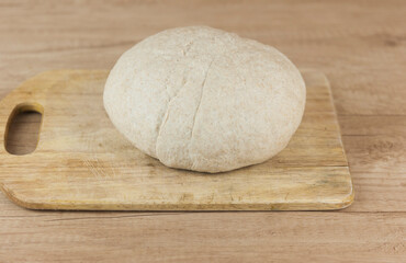 Risen or proved yeast dough for bread or pizza on wooden surface