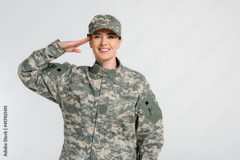 Wall mural woman in camouflage clothes saluting isolated on grey