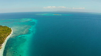 Aerial view of sandy beach on a tropical island with palm trees by coral reef atoll. Patongong Island with sandy beach. Summer and travel vacation concept.