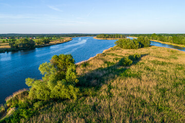 Fototapeta na wymiar The Odra River in Poland, in a section of the Śląskie Voivodeship, photographed during the golden hour. The beautiful blue color of the river and shades of yellow and green on land. 