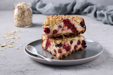 Homemade curd cheese casserole with oatmeal and cherry on a gray plate on light gray background,...